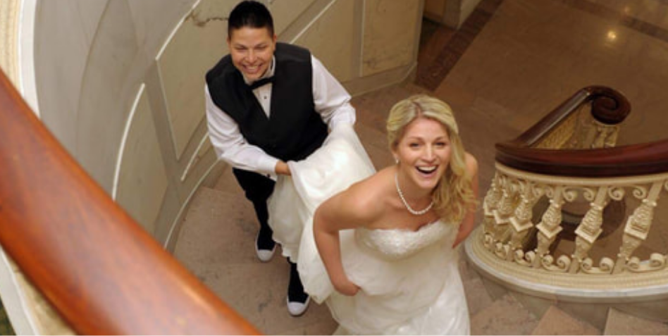 Bride walking up the stairs with person holding her dress